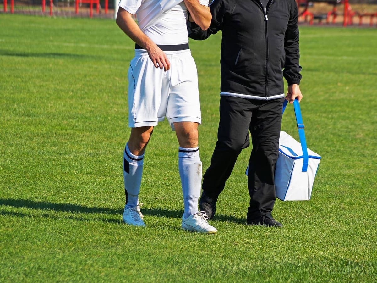 A player being helped off the field by a member of staff